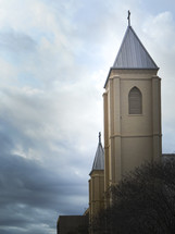 Church steeple rising through stormy clouds toward heaven.