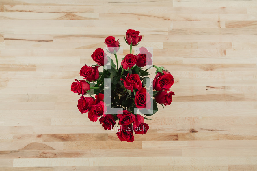 Red roses on a wooden table from above.