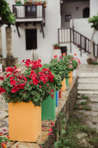 Colorful containers of flowers on a stone wall.