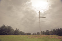 a cross on a hill under an overcast sky 