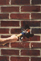 breaking a brick wall with a hammer 