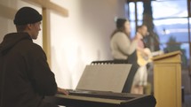 Worship in a congregation with lights, keyboard, guitar and box drum.