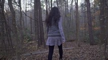 a woman walking through a forest 