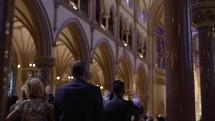 Congregation praying inside of a catholic/cathedral church during a ceremony.