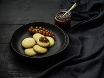 Cookies with jelly and berries on black table