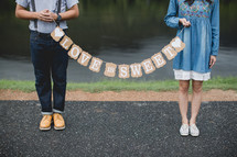 a couple holding a love is sweet banner 