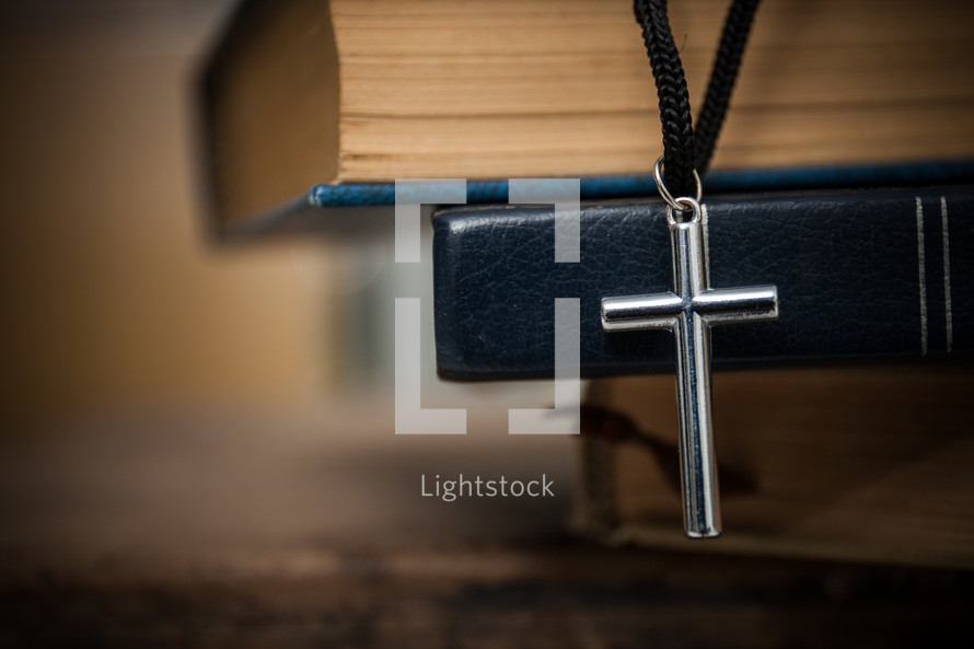 cross necklace on a stack of books 