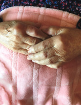 elderly hands on a pink blanket 