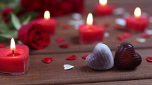 Valentines Day concept chocolate candies heart shaped and red roses with candles on wood. Love and romance concept. Dolly shot 4k