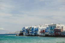 White and blue buildings along the shore of a blue sea.
