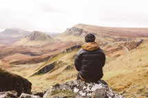 man sitting on a rock on slopes in Scotland 