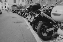 motorcycles and Vespas parked along a street in Italy 