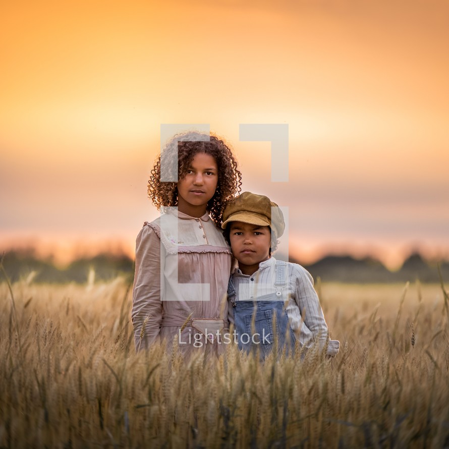 brother and sister standing in a field 