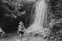 a woman walking in front of a waterfall 