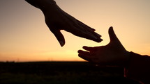 Mom and child holding hands together on sunset background. Silhouette as son or daughter takes mother hand. Sun flares. Family, trust, love and happiness concept. High quality 4k footage