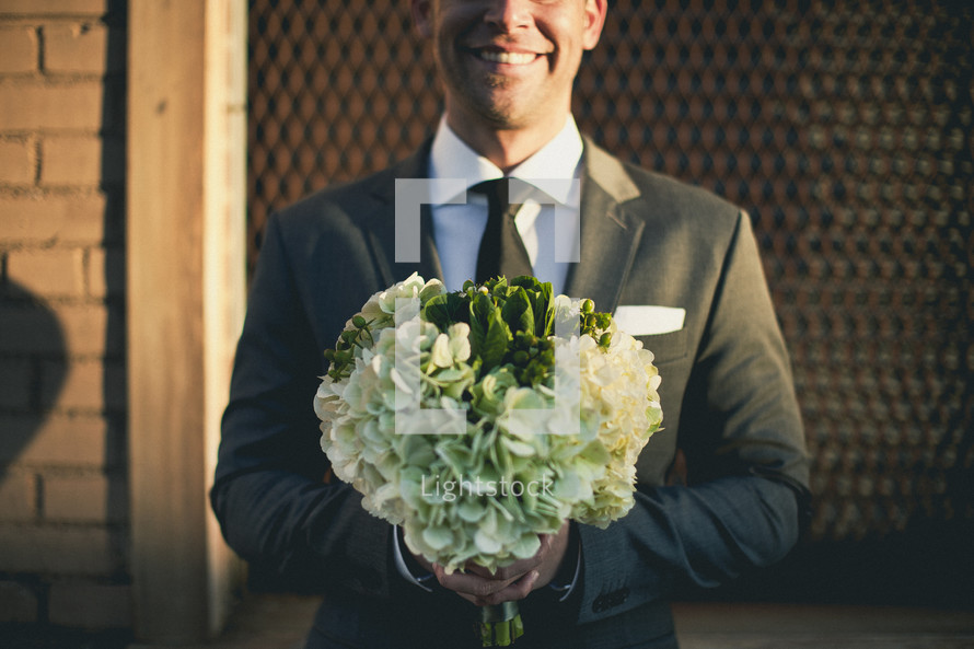 groom holding bridal bouquet