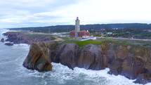 Waves crashing over rocks near island with lighthouse
