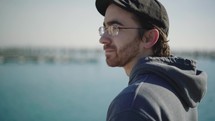 A contemplative young man looking out towards the lake at the harbor