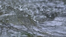Water waves flows in mountain stream background
