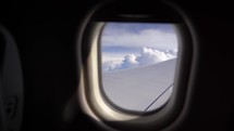 The view from the airplane window. Flying above the blue sky with moving clouds. Traveling on airplane. 