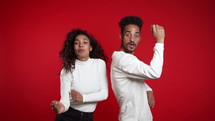 Young african american couple dancing isolated on red background studio. Party, happiness, music concept. Slow motion