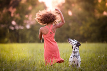 a girl dancing with her dog in a field 