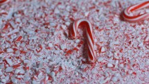 Candy canes falling in slow motion onto a pile of crushed candy canes