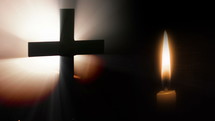 Cross and candle in the dark.
