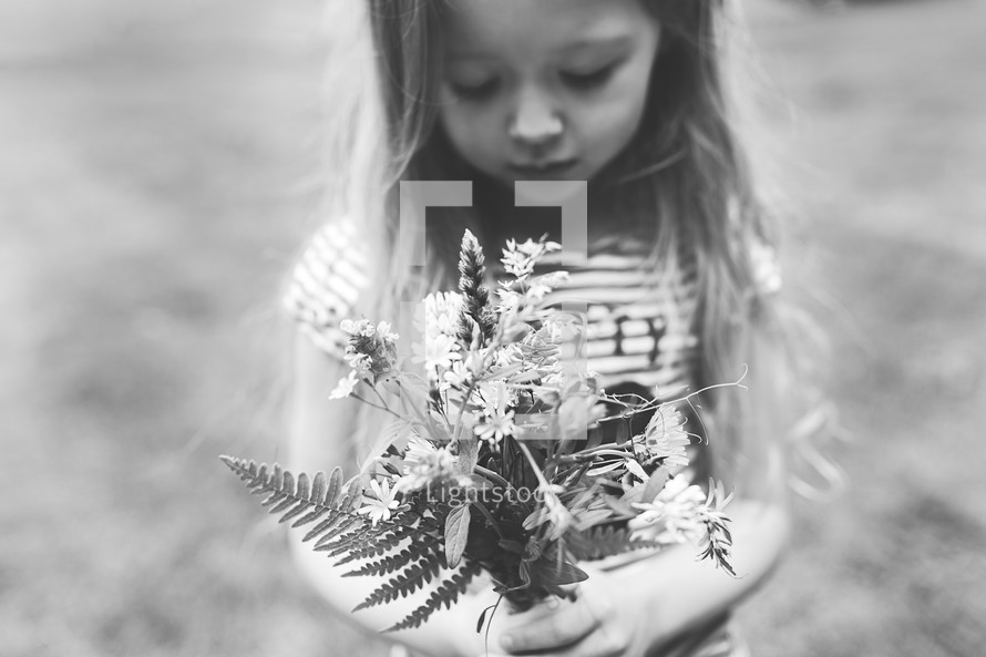little girl holding a bouquet of picked flowers 