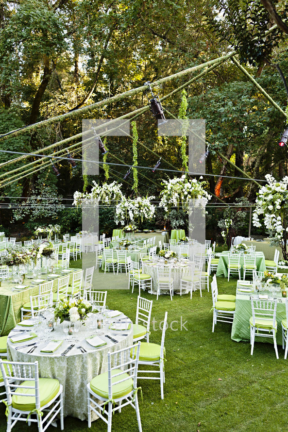 empty set tables before a wedding reception green, forest event, dinner party chairs tables flatware plates