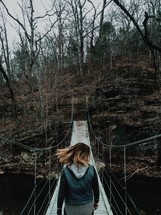 woman walking across a swinging bridge 