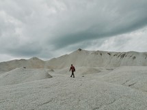 A lone man walking on a mountain of stone.