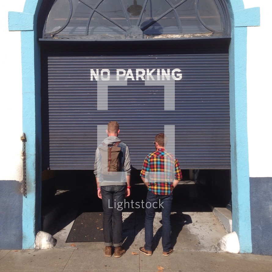 two men standing in front of a no parking sign 