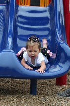 toddler girl sliding down a slide 