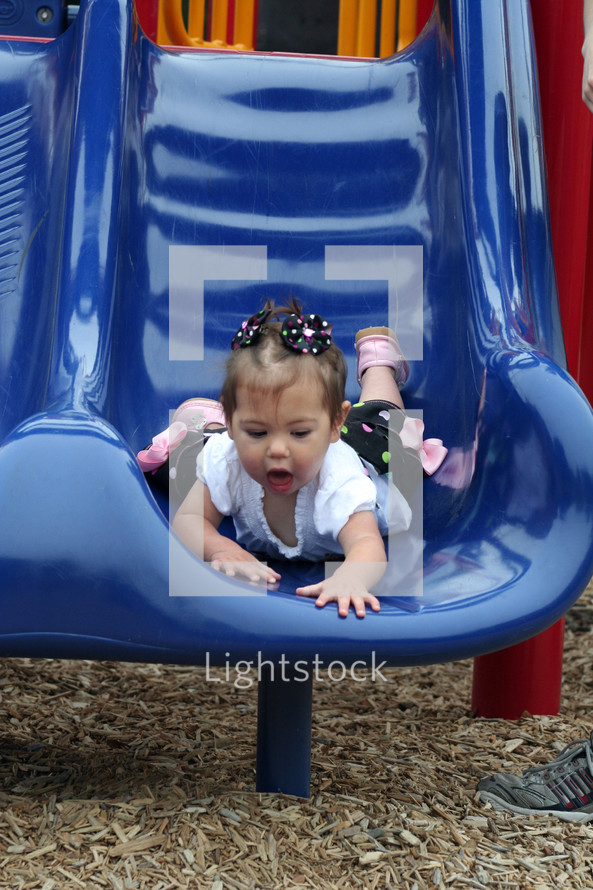toddler girl sliding down a slide 