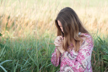 woman praying kneeling outdoors 