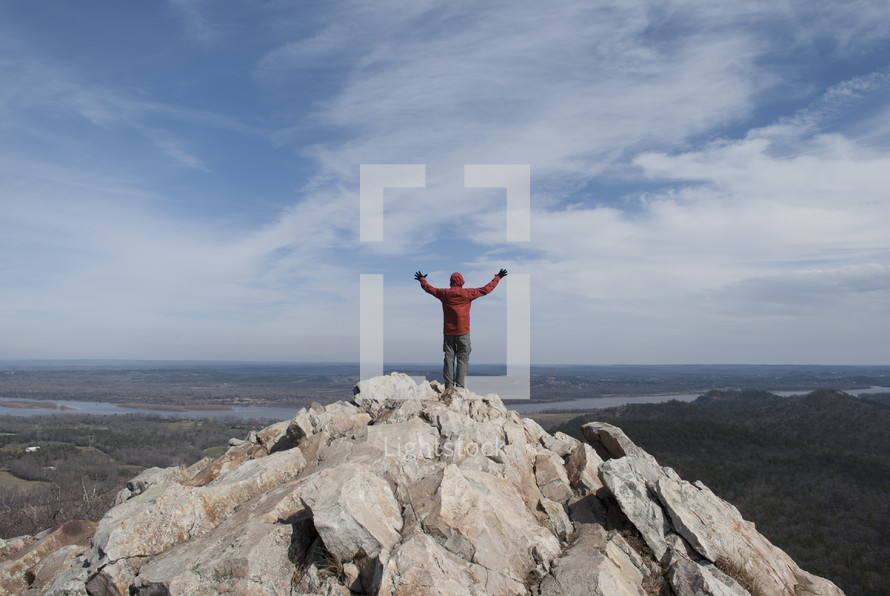 man standing on top of a mountain with his hands raised in worship to God