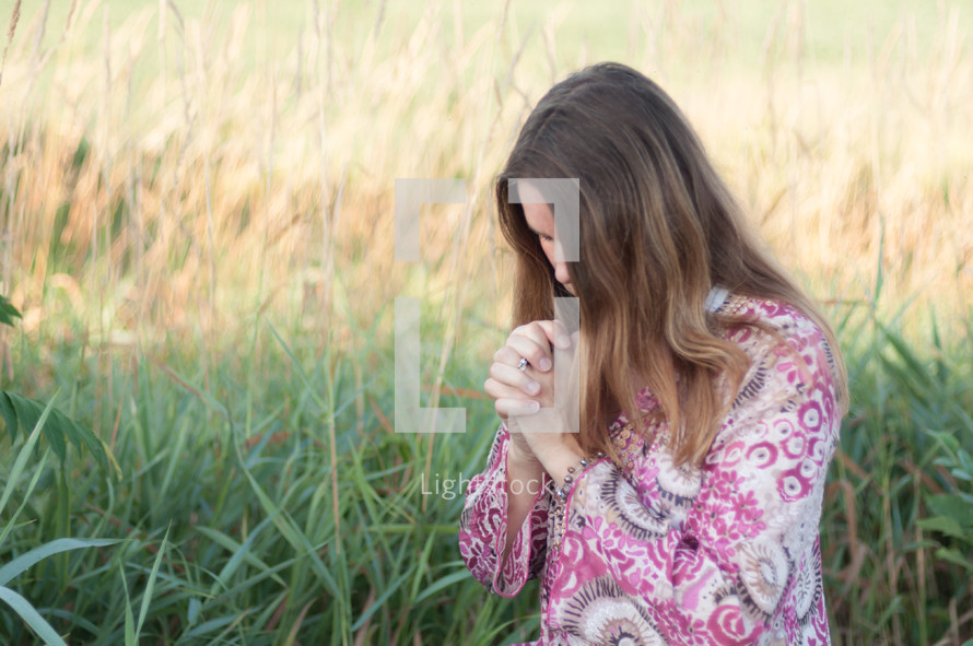 woman praying kneeling outdoors 