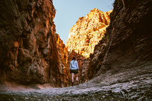 A woman hiking among steep cliffs.