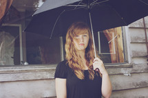 Pensive teen in the shelter of an umbrella