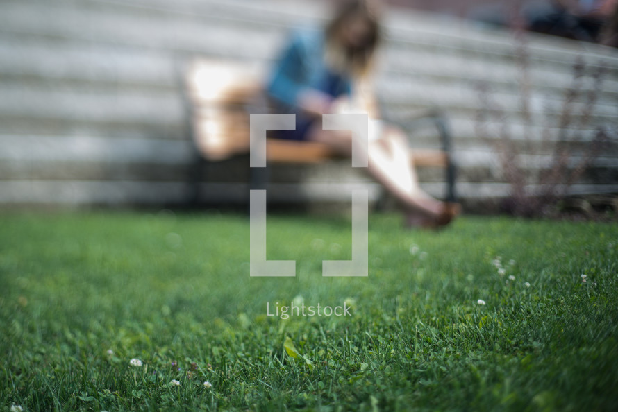blurry image of a woman sitting on a park bench 