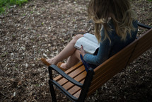 woman reading a Bible on a park bench 