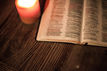open Bible on a table and a glowing candle