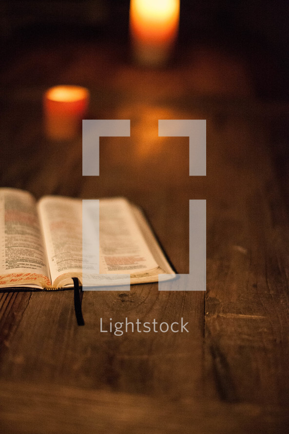open Bible on a table and burning candles