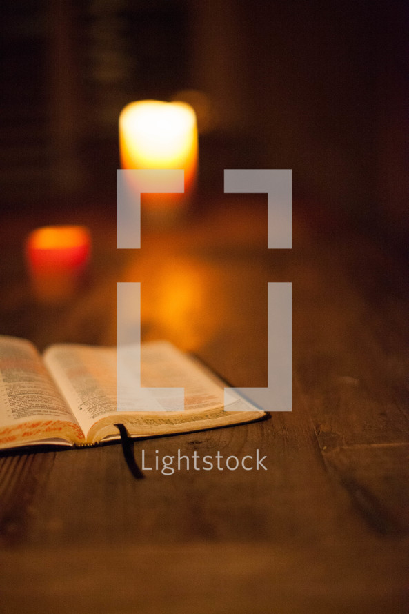 open Bible on a table and burning candles
