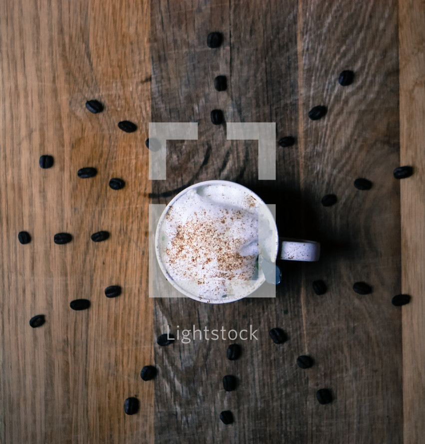 coffee cup with radiating coffee beans on wood 