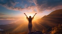 Happy woman with raised hands in the mountains on a background of the sunset
