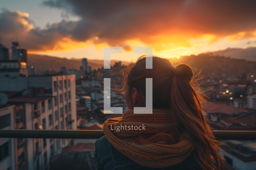 A woman looking out over a city at sunset