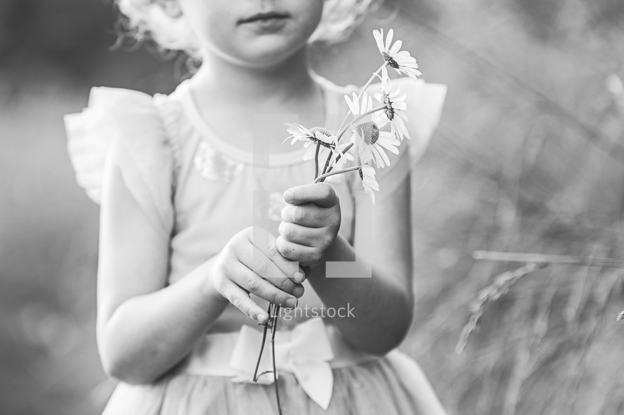 a little girl holding picked flowers 