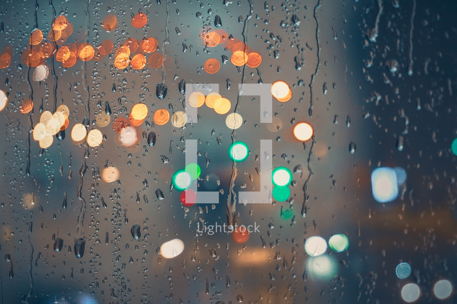 raindrops on the window and multi colored street lights at night background